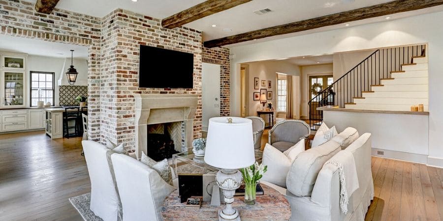 Transitional style living room with fireplace and exposed wood beams, remodeled by Southern Green Builders in Houston, Texas